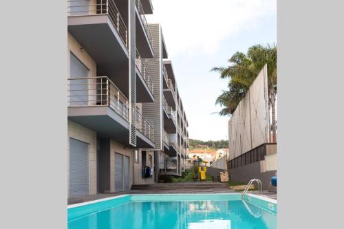 a building with a swimming pool in front of a building at Bay Residence Apartamento - Piscina in São Martinho do Porto