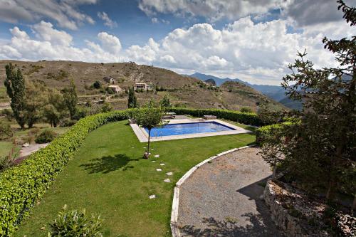 a garden with a swimming pool and a hill at Apartaments Cal Borda in Coll de Nargó