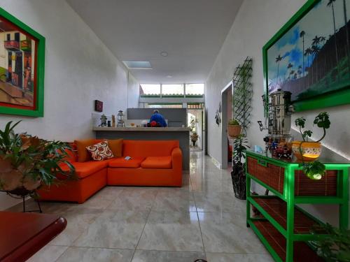 a living room with an orange couch and a kitchen at Hotel Casa Quinta Salento in Salento