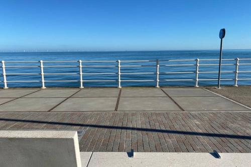 a bench next to the ocean with a fence at Luxury Modern 2Bed Seafront Apartment in Rhos on Sea in Colwyn Bay