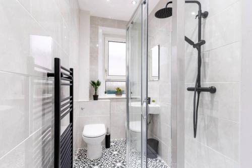 ein Badezimmer mit Toilette und Glasdusche in der Unterkunft Cheerful 2 Bedroom Homely Apartment, Sleeps 4 Guest Comfy, 1x Double Bed, 2x Single Beds, Free Parking, Free WiFi, Suitable For Business, Leisure Guest, Contractors, QE Hospital, Glasgow, Near Airport & City Centre in Glasgow