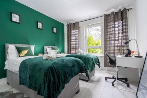 um quarto verde com 2 camas e uma secretária em Cheerful 2 Bedroom Homely Apartment, Sleeps 4 Guest Comfy, 1x Double Bed, 2x Single Beds, Free Parking, Free WiFi, Suitable For Business, Leisure Guest, Contractors, QE Hospital, Glasgow, Near Airport & City Centre em Glasgow