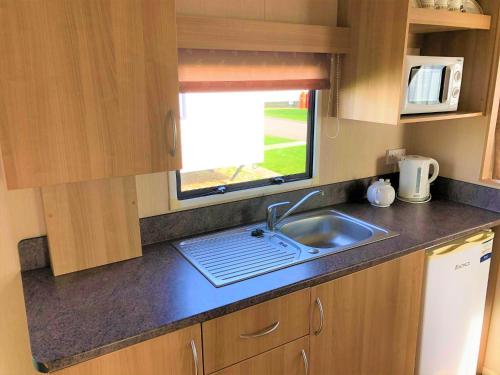 a kitchen counter with a sink and a window at Elder Standard Holiday Home in Ingoldmells