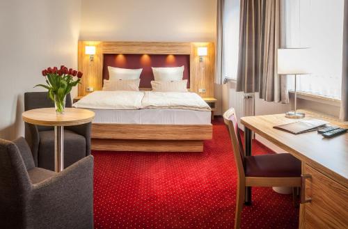 um quarto de hotel com uma cama e uma secretária em City Hotel em Bremerhaven