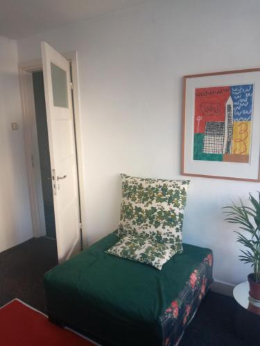 Cette chambre dispose d'un canapé vert avec un oreiller. dans l'établissement ETAGE voor 1-2 pers in NIJMEGEN-Centrum, à Nimègue