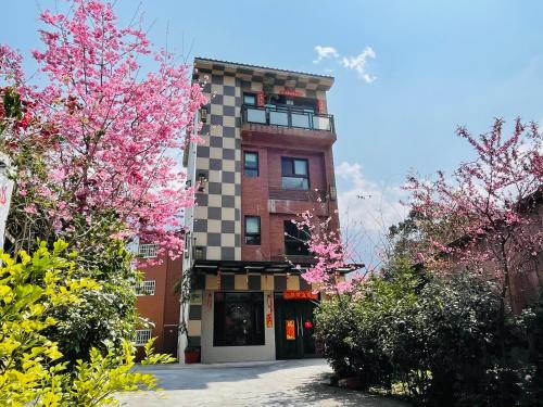 a building with pink flowering trees in front of it at Sin Ging Hong Resort in Lugu