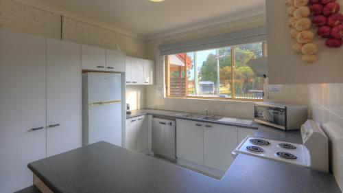 a kitchen with a white refrigerator and a window at Yamba Motor Inn in Yamba
