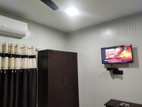 una habitación con TV en la pared y una habitación con en Vidhara Rooms, en Trivandrum