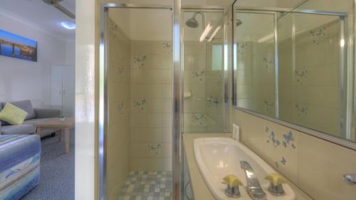 a bathroom with a shower and a bath tub at Yamba Motor Inn in Yamba