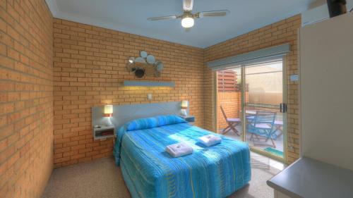 a bedroom with a bed and a brick wall at Yamba Motor Inn in Yamba