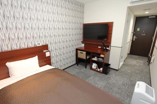 a bedroom with a bed and a flat screen tv at Hotel 1-2-3 Fukuyama in Fukuyama