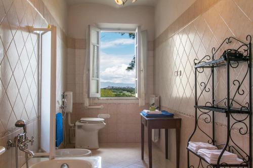 a bathroom with a window and a toilet and a sink at Villa La Fontana in Castiglione del Lago