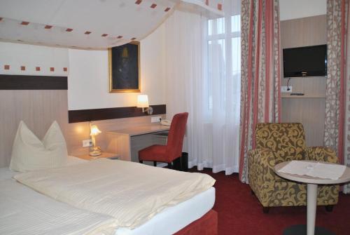 a hotel room with a bed and a desk and a chair at Hotel Wuppertaler Hof in Remscheid