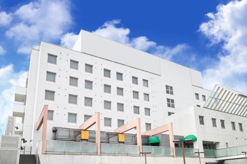 un edificio blanco con un cielo en el fondo en AkishimaStationHotel TOKYO, en Akishima