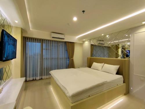 a bedroom with a large white bed and a window at Platinum 1012 Studio Tera Apartemen Bandung City View in Bandung