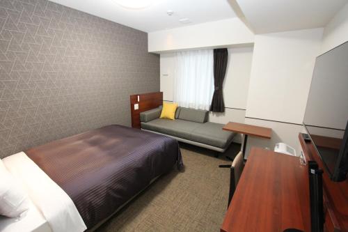a hotel room with a bed and a couch at Hotel 1-2-3 Fukuyama in Fukuyama