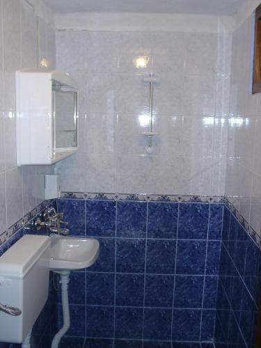 a blue tiled bathroom with a sink and a toilet at Sarafova Guest House in Koprivshtitsa