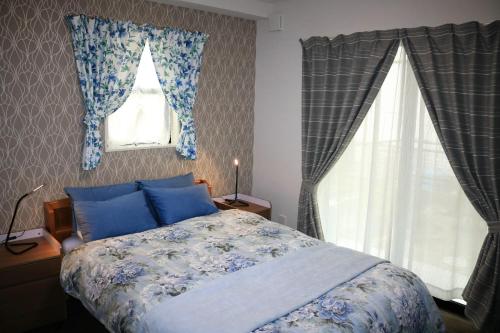 a bedroom with a bed with blue pillows and windows at Chiyoda-Home　Osu-sakae-Subways-JR trin-Spa-parking spot-WIFI in Nagoya