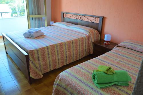 two beds in a hotel room with towels on them at Hotel Villa del Sole in Porto Cesareo