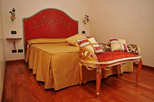 a bed with a red head board and a chair at Hotel Patriarchi in Aquiléia
