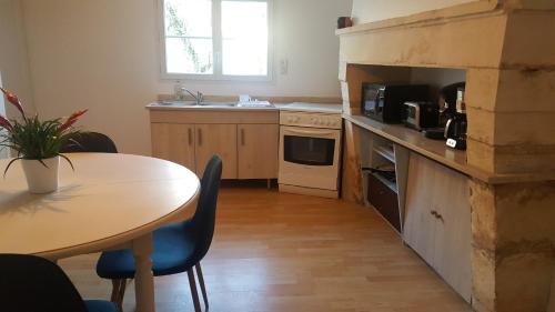 une cuisine avec une table, une table et un comptoir dans l'établissement L'âtre de l'Abeilloire, à Chabournay