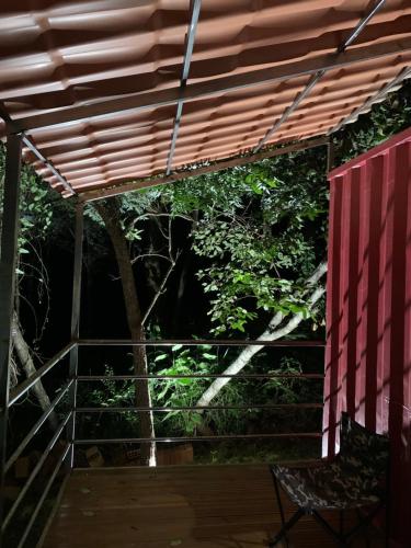 a wooden deck with a chair under a pergola at Pousada Cipó Container Chalés Privativos com lareira - Centro da cidade in Serra do Cipo
