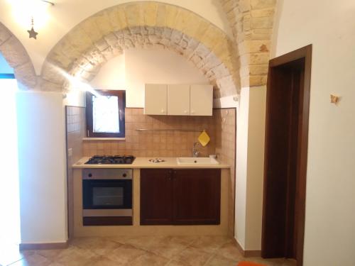 a kitchen with an archway with a stove and a sink at Soggiornare In Centro in Alberobello
