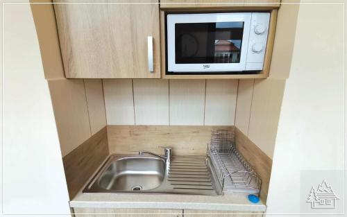eine Küche mit einer Spüle und einer Mikrowelle in der Unterkunft Przystanek Rabka - Apartamenty w centrum in Rabka-Zdrój