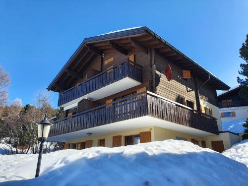 un grand bâtiment avec un balcon dans la neige dans l'établissement Chalet Alba A, à Bürchen