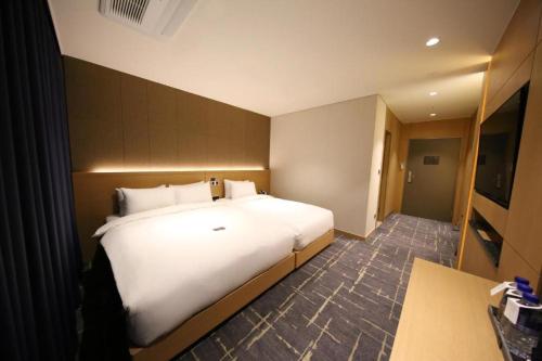 a bedroom with a large white bed and a desk at Sea Cruise Hotel in Sokcho