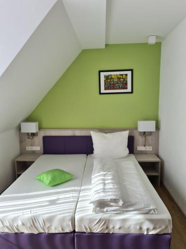 a bed in a room with a green wall at Hotel Gasthof zum Engel in Künzelsau