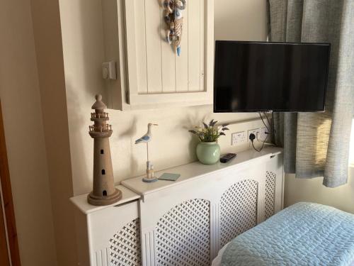 a tv on top of a white dresser with a lighthouse at The Peels B&B in Lowestoft