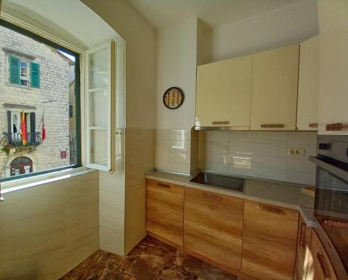 una cocina con armarios de madera y un reloj en la pared en Old Town Sea Gate Apartment, en Kotor