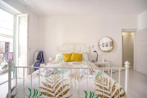 a bedroom with a white bed with yellow pillows at La Baia di Ortigia in Syracuse