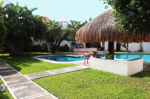 a yard with a swimming pool with a straw hut at Casa Wilo in Cancún