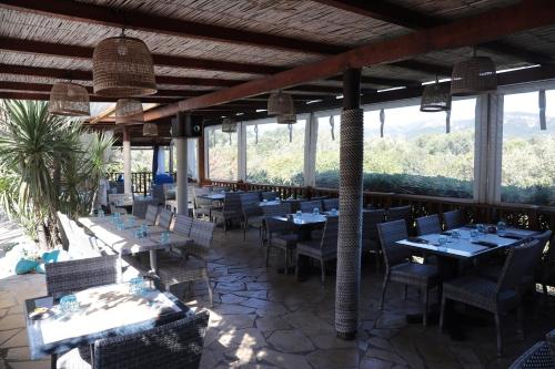 un restaurante con mesas, sillas y ventanas en Residence Fium Del Cavo, en Sainte-Lucie de Porto-Vecchio