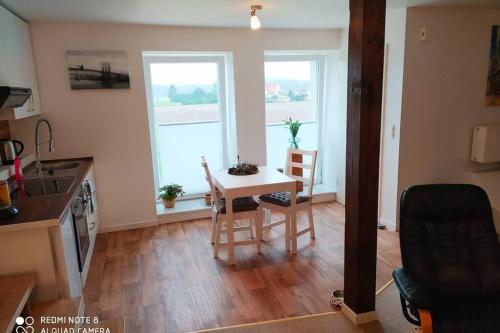 a kitchen and dining room with a table and two windows at Studiowohnung in Bergen/Bleckmar in Bergen