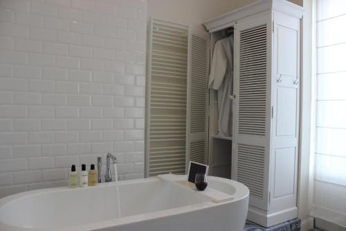 a white bath tub in a bathroom with a window at The Hamptons Boutique Hotel in Ghent