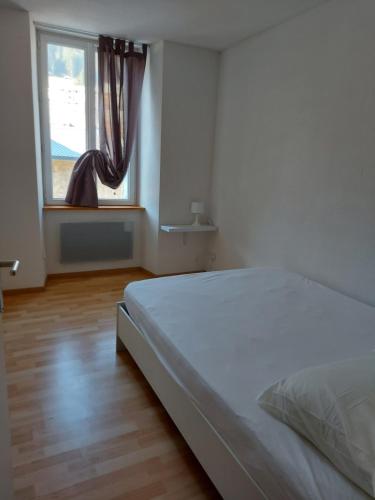 een slaapkamer met een wit bed en een raam bij Chez sylvie in Morez