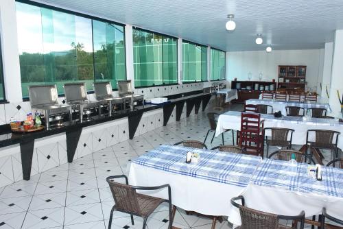 a restaurant with white tables and chairs and large windows at Hotel Fazenda Villa Galicia in Nazaré Paulista