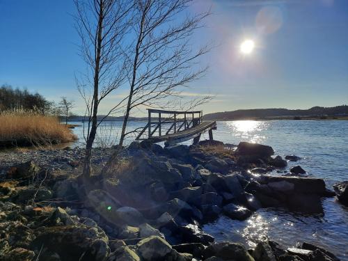 a dock on a lake with the sun in the sky at Gårdslägenhet nära Göteborg in Alvhem