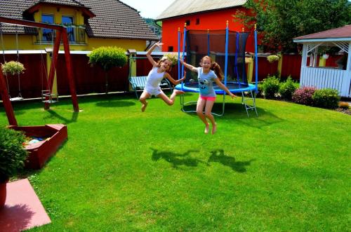 duas crianças a saltar num trampolim num quintal em Vila Deluxe & Apartmány Riviéra Liptov Bešeňová em Bešeňová