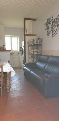 a living room with a black leather couch and a table at Gîte Le Campagnard in Saint-Germain-des-Bois