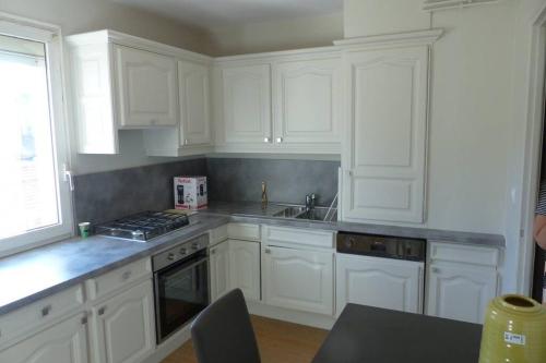 une cuisine blanche avec des armoires blanches et un évier dans l'établissement Lumineux T3-93m2- -2 loggias- vue sur Mont Saint-Clair, à Sète