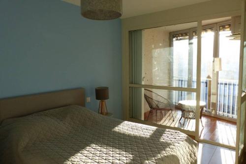 une chambre avec un lit et une fenêtre avec un balcon dans l'établissement Lumineux T3-93m2- -2 loggias- vue sur Mont Saint-Clair, à Sète