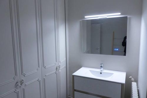 une salle de bain blanche avec un lavabo et un miroir dans l'établissement Lumineux T3-93m2- -2 loggias- vue sur Mont Saint-Clair, à Sète