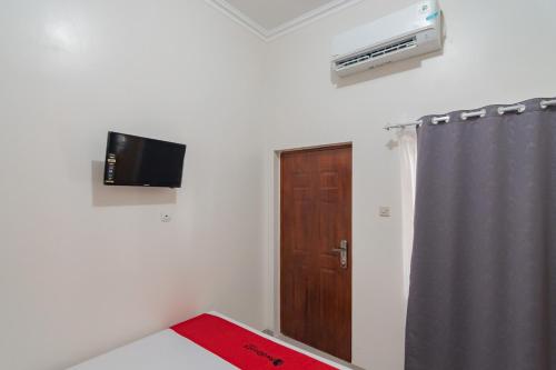 a room with a door and a television on the wall at RedDoorz Syariah Plus @ Perintis Guesthouse Tasikmalaya in Tasikmalaya