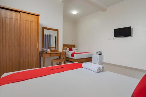 a hotel room with a bed and a desk at RedDoorz Syariah Plus @ Perintis Guesthouse Tasikmalaya in Tasikmalaya