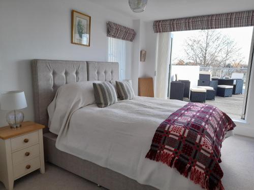 a bedroom with a large bed with a plaid blanket at Crow's Nest in Somerford Keynes