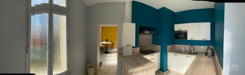 a kitchen with white cabinets and a blue wall at Le Charles VII - VIENNE in Chinon